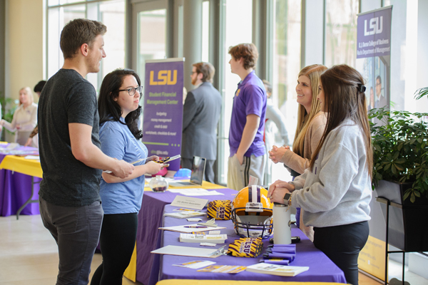Two people at a table during a career fair talking to represetative of organization.