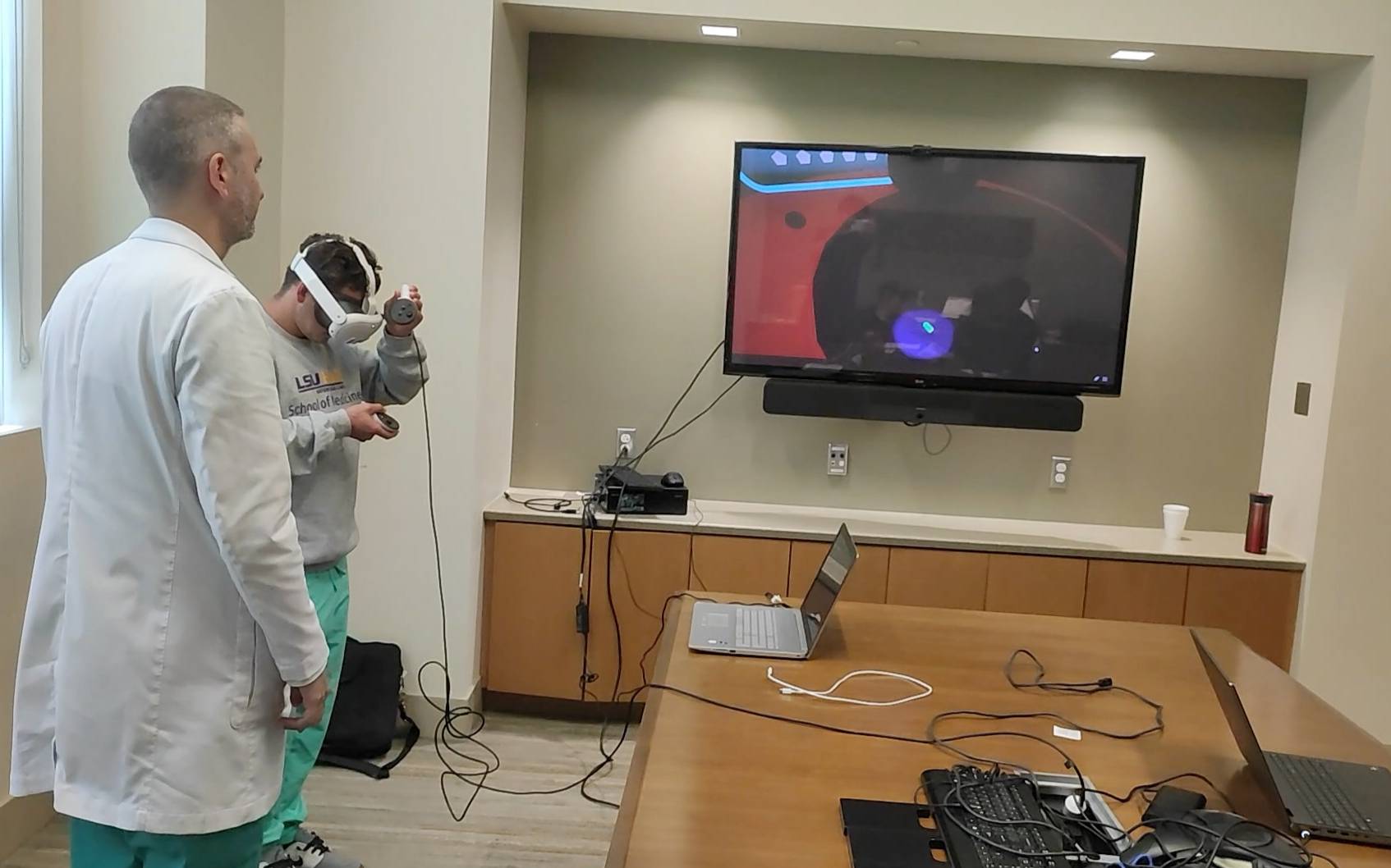 Photo of med students wearing VR goggles training on the middle line procedure.