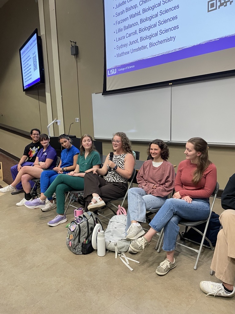 students sitting on chairs participating in a panel discussion